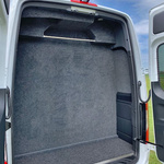 Grey luggage compartment with clothes rail in minibus